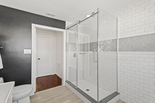 full bathroom with visible vents, a shower stall, toilet, and wood finished floors