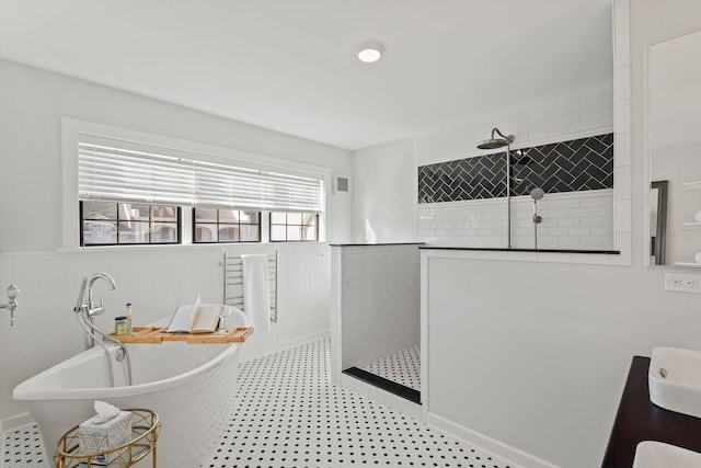 full bath featuring visible vents, a wainscoted wall, a freestanding tub, a sink, and a walk in shower