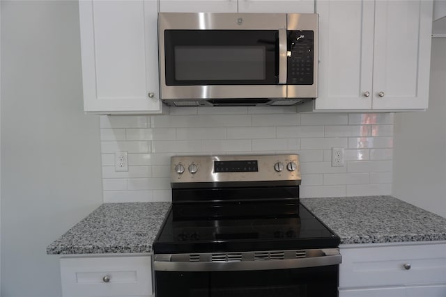 kitchen with light stone counters, range with electric stovetop, white cabinetry, stainless steel microwave, and tasteful backsplash