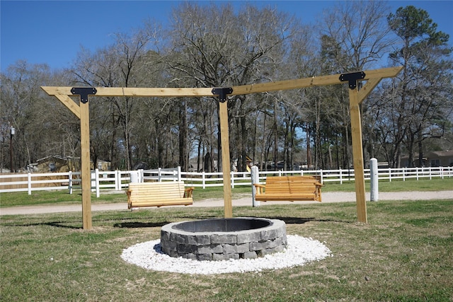 view of property's community featuring a yard, an outdoor fire pit, and fence