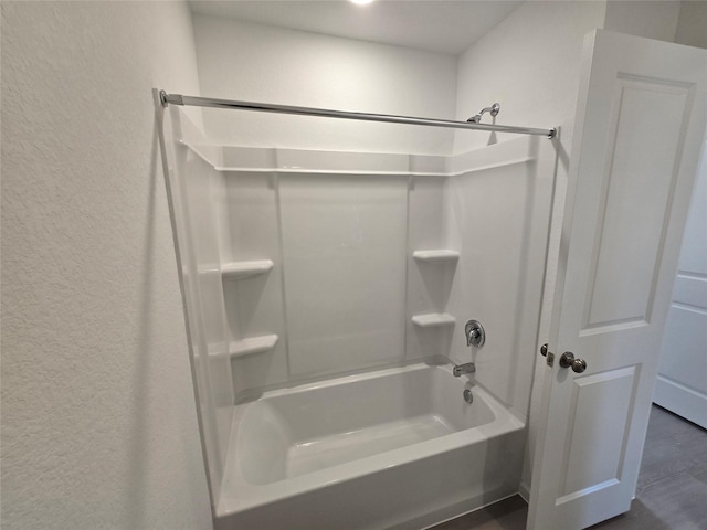 bathroom featuring shower / bathing tub combination and a textured wall