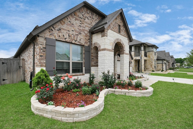 view of front of property featuring a front yard, brick siding, and stone siding