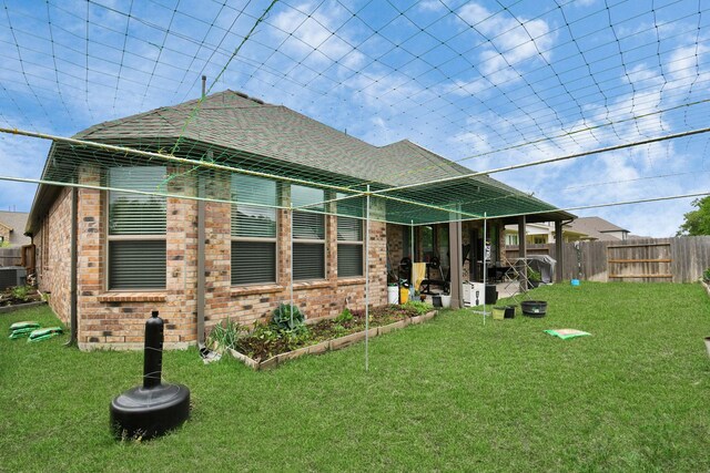 rear view of property featuring brick siding, fence, and a lawn