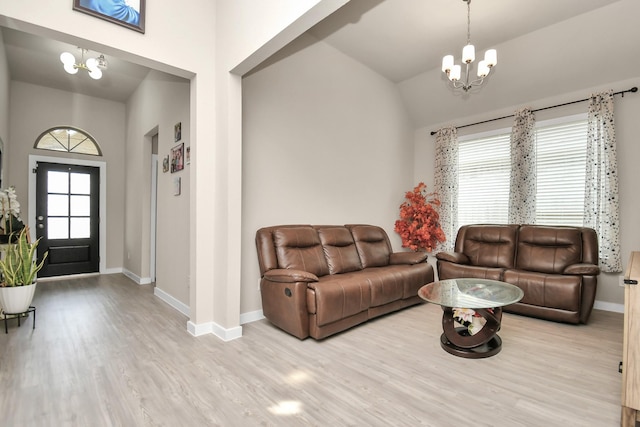 living area with baseboards, lofted ceiling, an inviting chandelier, and wood finished floors