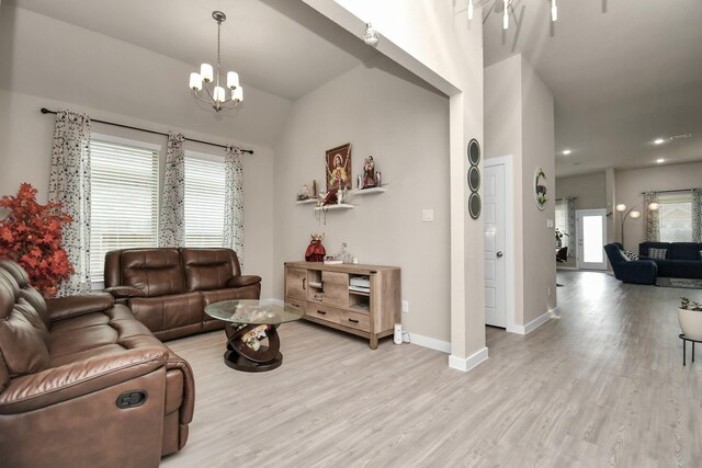 living area featuring an inviting chandelier, baseboards, and light wood finished floors