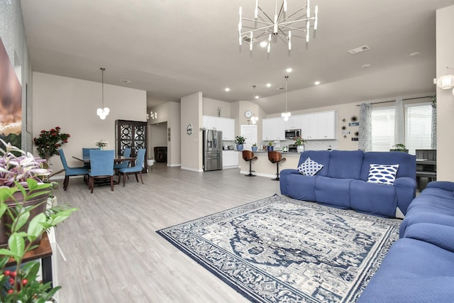 living room featuring light wood-type flooring, visible vents, recessed lighting, an inviting chandelier, and lofted ceiling