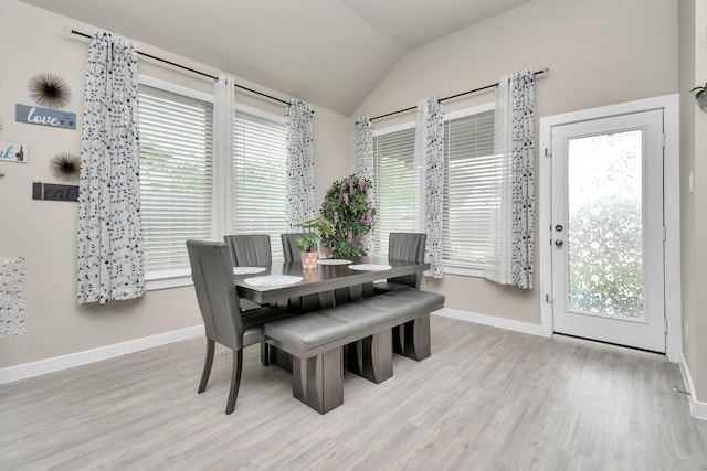 dining space featuring lofted ceiling, wood finished floors, and baseboards