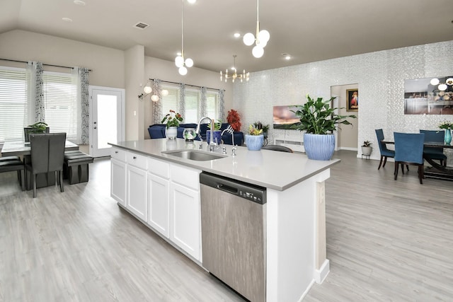 kitchen featuring an island with sink, a sink, stainless steel dishwasher, white cabinetry, and light wood-style floors