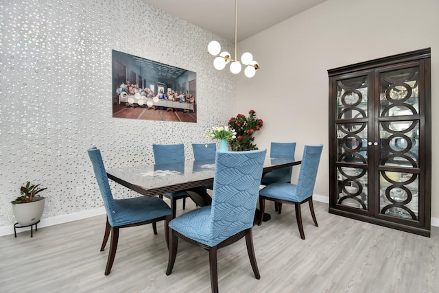 dining room with an accent wall, wood finished floors, baseboards, and wallpapered walls