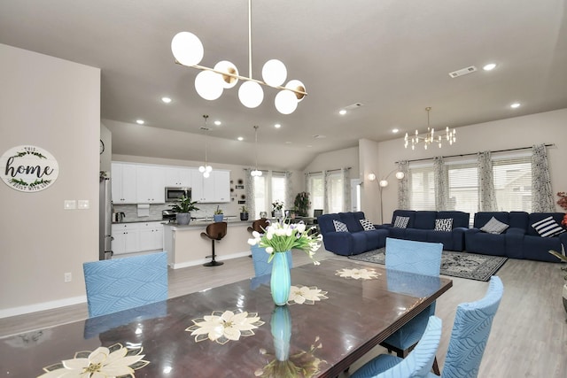 dining space featuring visible vents, lofted ceiling, recessed lighting, light wood-style floors, and a notable chandelier