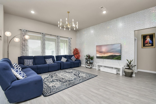 living area featuring a notable chandelier, wood finished floors, recessed lighting, baseboards, and an accent wall