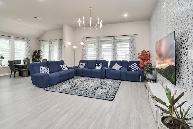 living area featuring wood finished floors, baseboards, visible vents, vaulted ceiling, and a chandelier