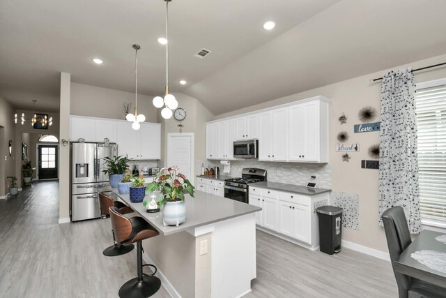 kitchen featuring visible vents, a kitchen island, stainless steel appliances, a kitchen bar, and backsplash