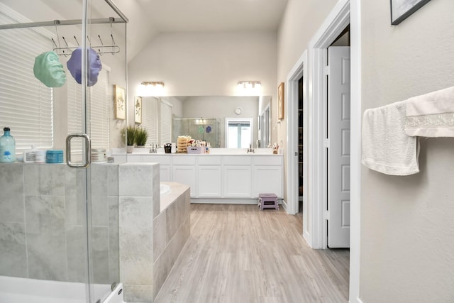 full bathroom featuring wood finished floors, a shower stall, lofted ceiling, a bath, and vanity