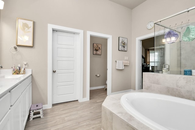 full bath with a bath, a stall shower, vanity, and wood finished floors