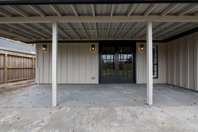 property entrance with a patio area, fence, and board and batten siding