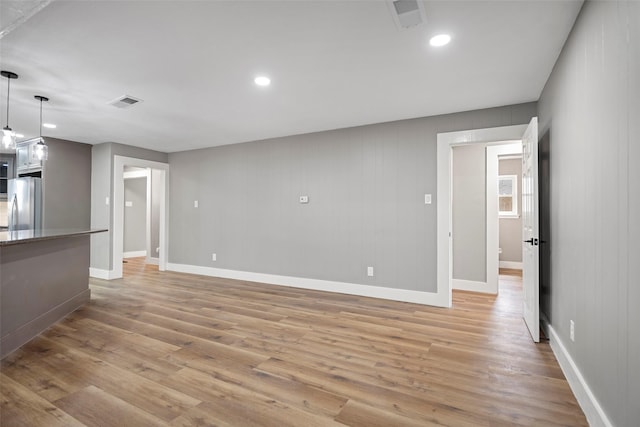 unfurnished living room featuring visible vents, light wood-type flooring, and baseboards