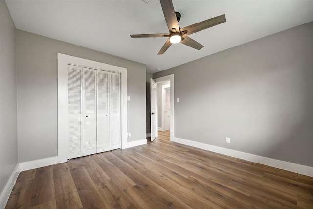 unfurnished bedroom with wood finished floors, baseboards, a closet, and ceiling fan