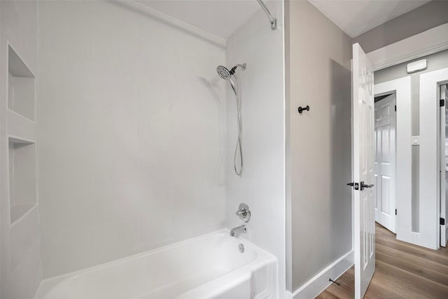 full bath featuring baseboards, shower / washtub combination, and wood finished floors