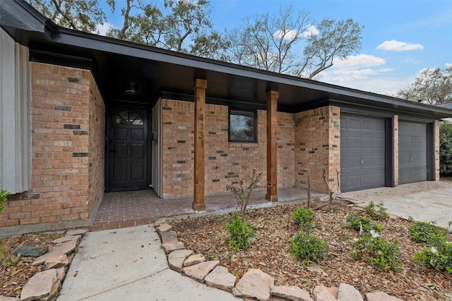 property entrance with brick siding, an attached garage, and concrete driveway