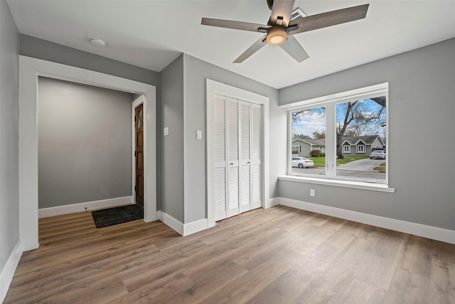 unfurnished bedroom featuring ceiling fan, wood finished floors, a closet, and baseboards