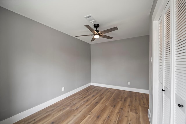 unfurnished bedroom featuring wood finished floors, baseboards, visible vents, ceiling fan, and a closet