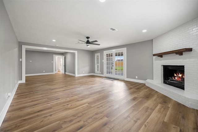 unfurnished living room featuring visible vents, a fireplace, baseboards, and wood finished floors