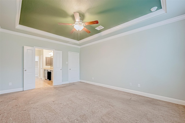 spare room with light carpet, visible vents, crown molding, and a tray ceiling