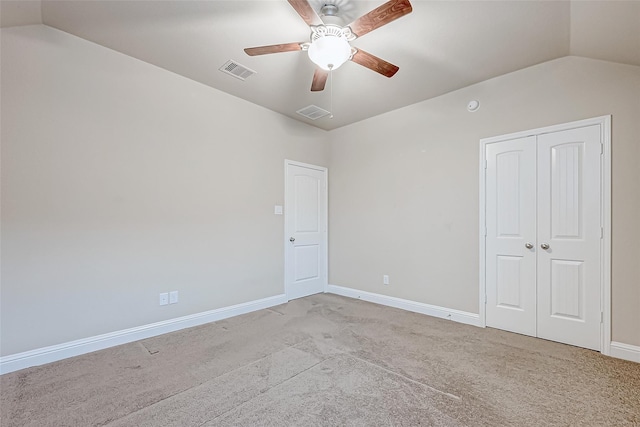 carpeted empty room with visible vents, baseboards, ceiling fan, and vaulted ceiling