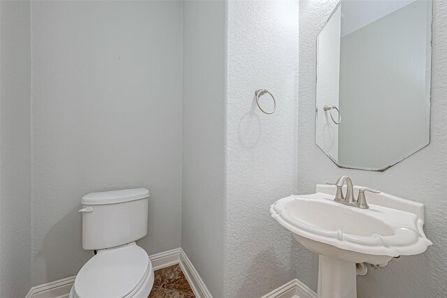 half bath with a sink, baseboards, and toilet