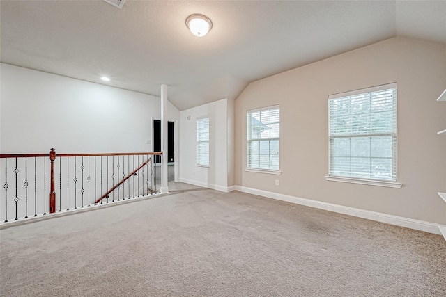 carpeted spare room with baseboards and vaulted ceiling