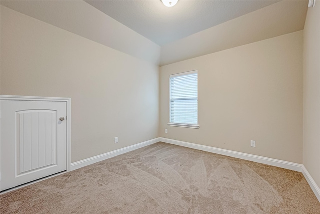 carpeted empty room featuring baseboards and lofted ceiling