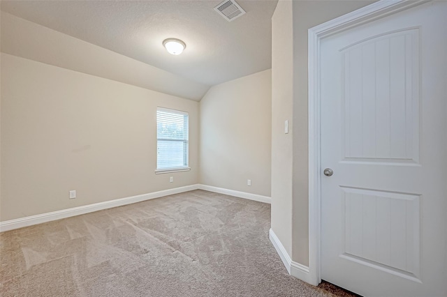 empty room with visible vents, carpet flooring, baseboards, and vaulted ceiling