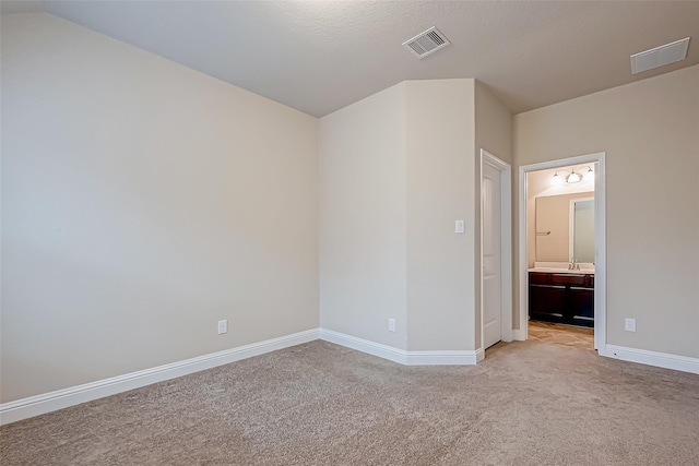 unfurnished bedroom with visible vents, baseboards, light colored carpet, and connected bathroom