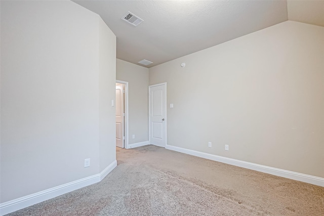 unfurnished room with visible vents, baseboards, light colored carpet, and lofted ceiling