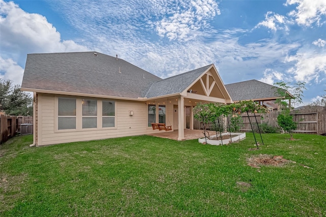 back of house with a patio, a lawn, a fenced backyard, and a shingled roof