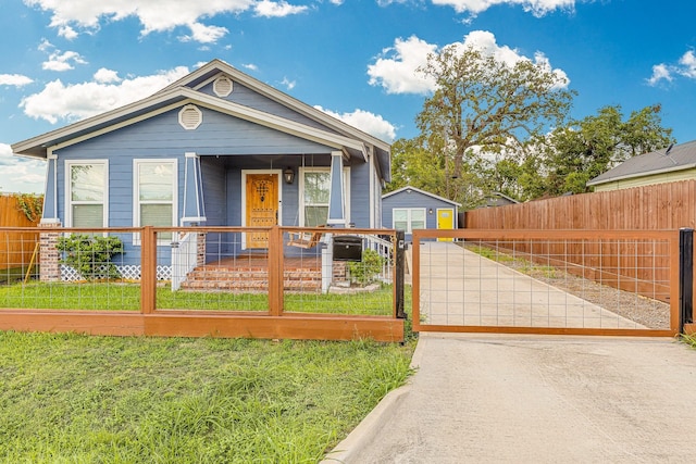 view of front facade with a fenced front yard, a porch, a front lawn, and a gate