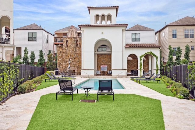 back of property with a lawn, a tiled roof, a patio, and fence