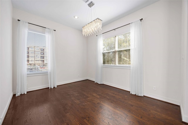 empty room with dark wood finished floors, a notable chandelier, recessed lighting, and baseboards