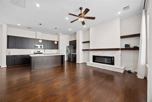 kitchen with dark wood-style flooring, decorative backsplash, light countertops, appliances with stainless steel finishes, and open floor plan