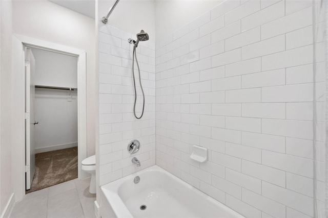 full bath featuring baseboards, tile patterned flooring, a walk in closet, shower / bathing tub combination, and toilet