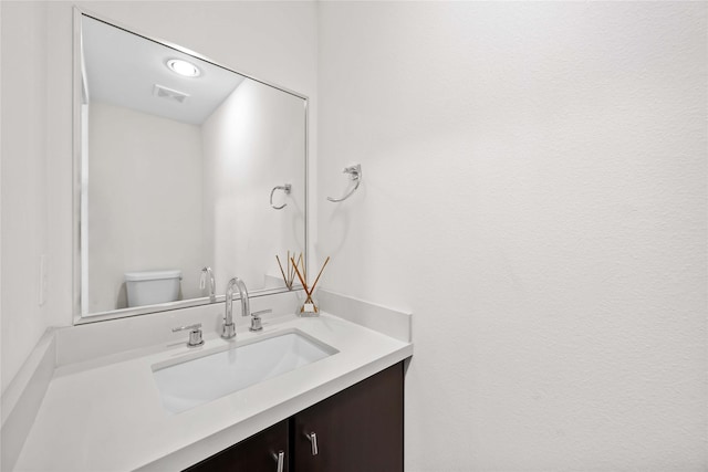 bathroom with vanity, toilet, and visible vents