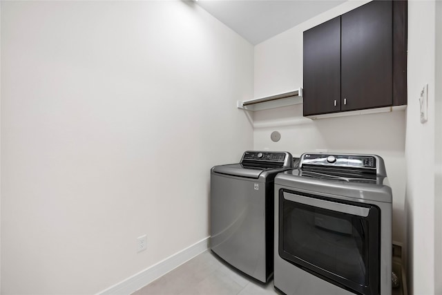 laundry room with washing machine and dryer, cabinet space, and baseboards