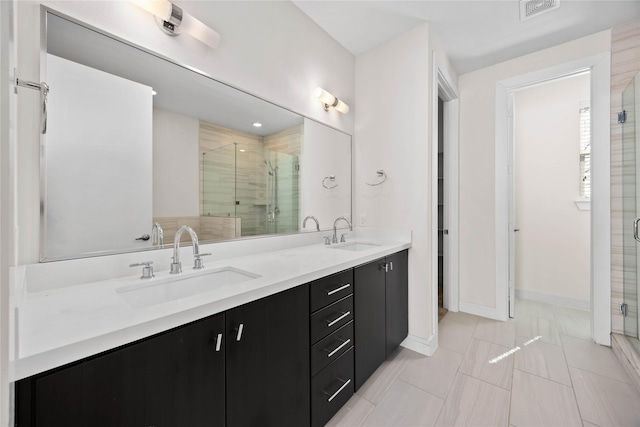 bathroom with double vanity, a stall shower, baseboards, and a sink