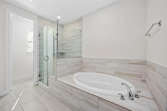 bathroom featuring a shower stall, a bath, and baseboards