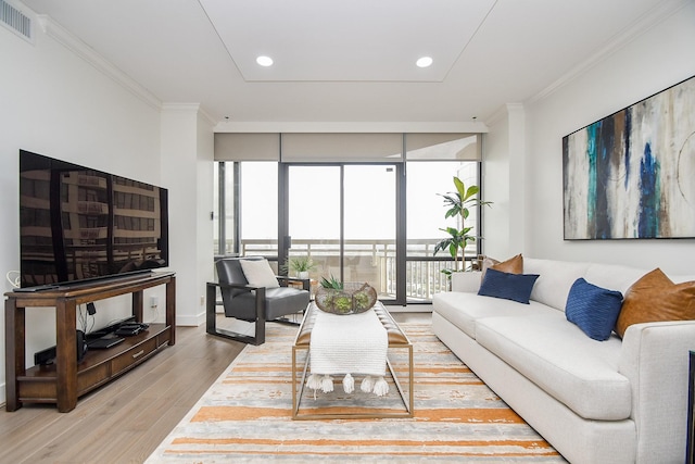 living area with visible vents, light wood-type flooring, crown molding, and expansive windows