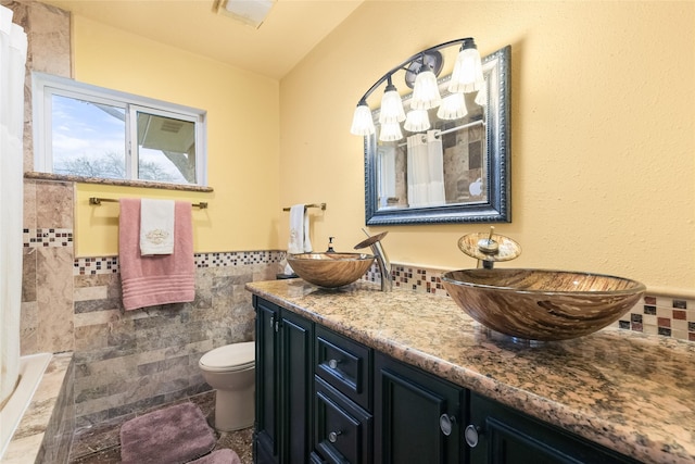 full bath featuring tile walls, double vanity, a tile shower, and a sink