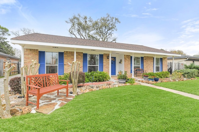 single story home with brick siding, a porch, a front yard, and fence