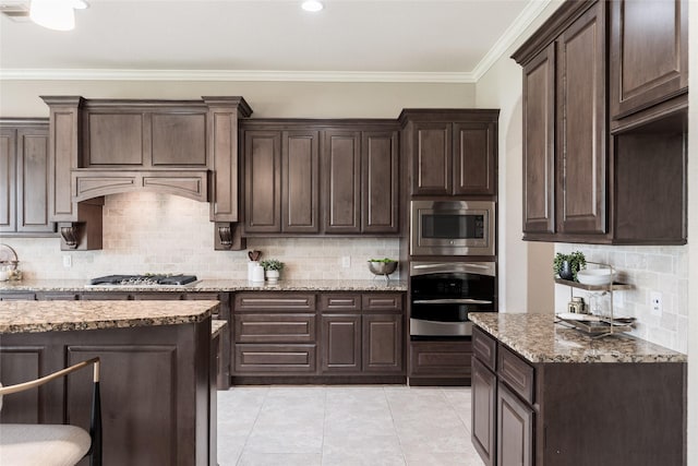 kitchen with light tile patterned floors, light stone countertops, ornamental molding, dark brown cabinetry, and appliances with stainless steel finishes