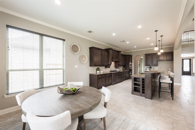 dining room featuring visible vents, arched walkways, baseboards, and ornamental molding